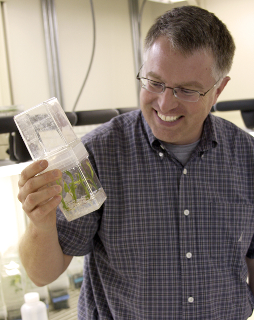 Charlie Brummer holds a container of soy beans in his lab in Athens.