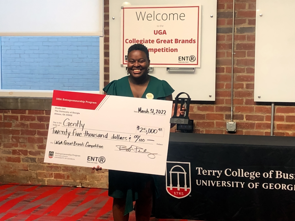 Kristen Dunning holds giant $25K check on stage of the UGA Great Brands Competition