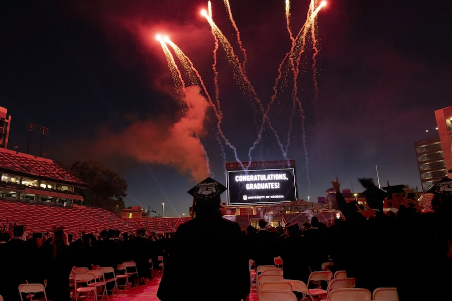 Fireworks go off at a UGA commencement ceremony at Sanford Stadium, where the scoreboard reads "Congratulations, graduates!"