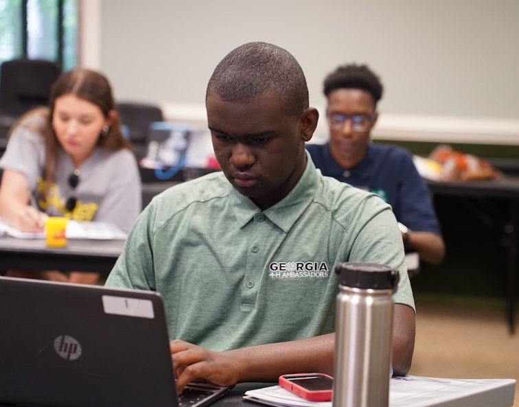 Three Georgia 4-H ambassadors use laptops in a classroom setting