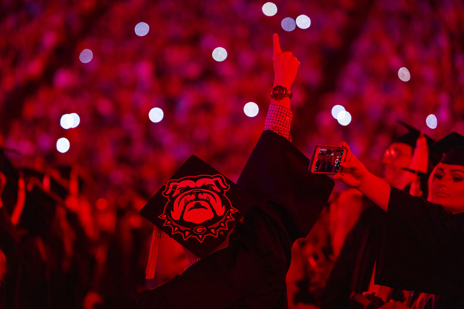 Students are illuminated in red light during spring 2022 undergraduate Commencement at Sanford Stadium. (Photo by Chamberlain Smith/UGA)
