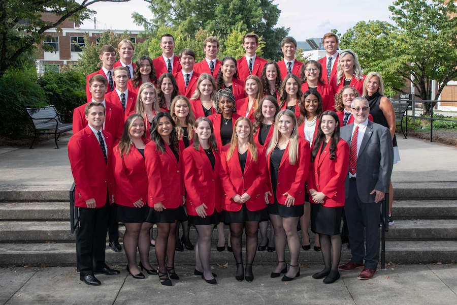 The 2022-23 CAES Ambassadors, all in red blazers, gather outside with CAES Dean Nick Place.