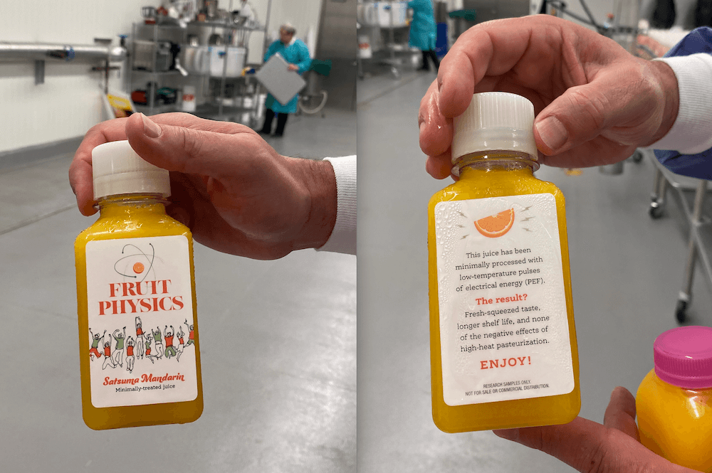 From left, UGA FoodPIC Director Jim Gratzek displays the front and back of a bottled sample of the minimally processed Georgia-made satsuma orange juice. The label of the research sample displays the Food Physics brand name. The back label reads "This juice has been minimally processed with low-temperature pulses of electrical energy (PEF). The result? Fresh-squeezed taste, longer shelf life, and none of the negative effects of high-heat pasteurization. ENJOY!"