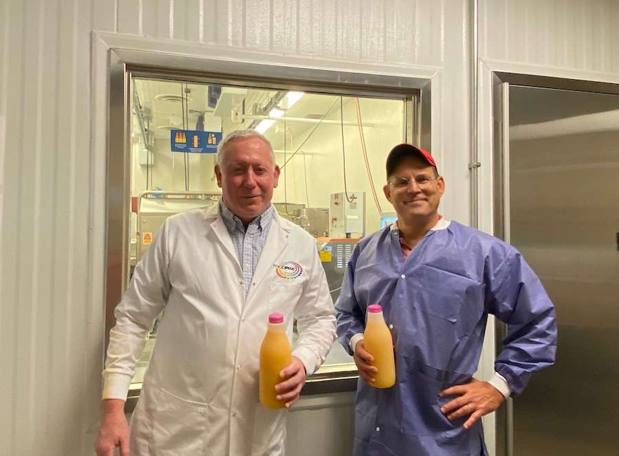 While standing side-by-side in the lab, Steve Hellenschmidt, of Food Physics, and Gratzek, of FoodPIC, show off the pulsed electric field, or PEF, processed orange juice samples made at FoodPIC at UGA-Griffin.