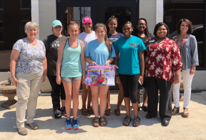 Participating members of Well Connected Communities pose with an activity mat they made for people with Alzheimer's at the local nursing home.