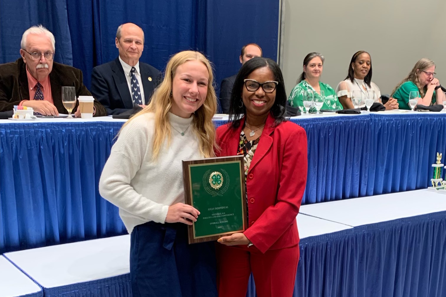 Lexi Pritchard (left) receives her top award from a member of the Poultry Science Association. The two are standing in front of a panel of national judges.