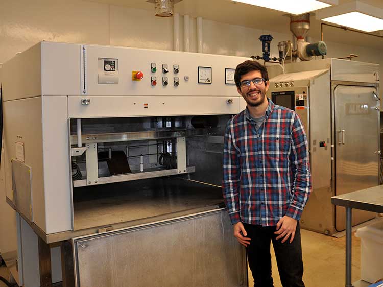 Altin Ozan stands next to lab equipment