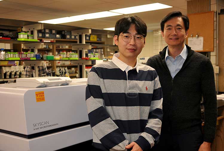 Postdoctoral researcher Jihwan Lee and Professor Woo Kyun Kim stand next to a piece of equipment in Kim's lab.