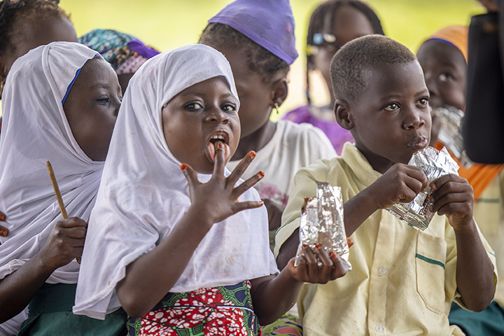 A young Ghanaian schoolgirl eats a peanut butter snack