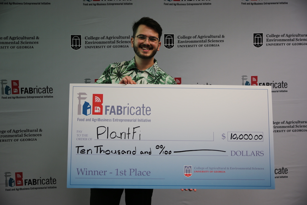 Plantfi founder Alex Breazu poses with a $10,000 check for winning the 2023 FABricate contest.