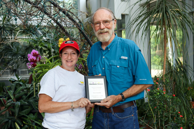 Beck Griffin presents Don Hunter with a plaque naming him the Grand Marshal of the 2023 Great Southeast Pollinator Census. 