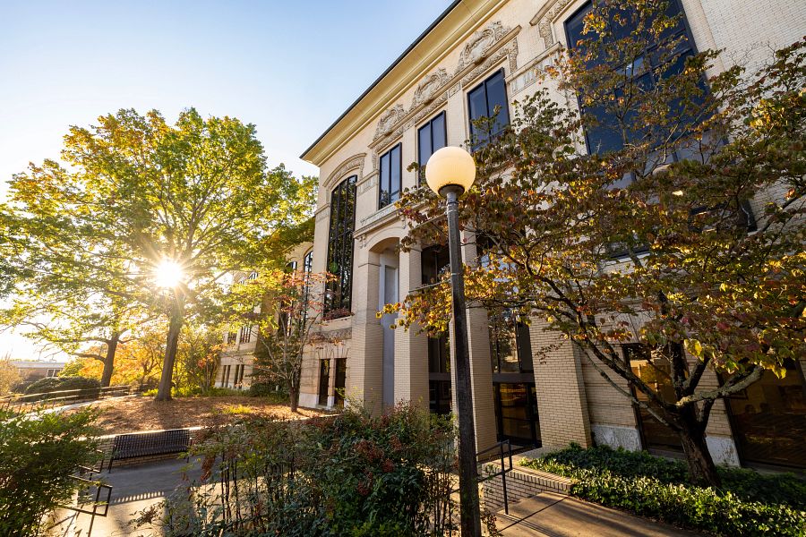 Early morning view of Conner Hall with sunlight filtering through trees starting to turn with colorful fall leaves.