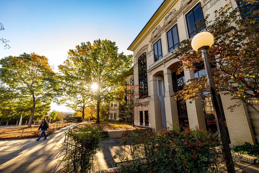 A student walks in front of Conner Hall in autumn sunshine