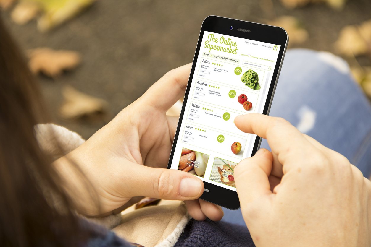 Close-up of a woman holding a smartphone and shopping for groceries online