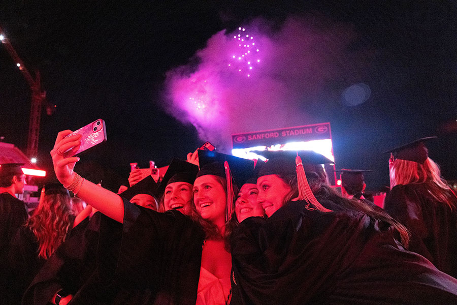 Graduating students take selfie photos during the fireworks display at UGA's 2023 undergraduate Commencement ceremony at Sanford Stadium. By Dorothy Kozlowski