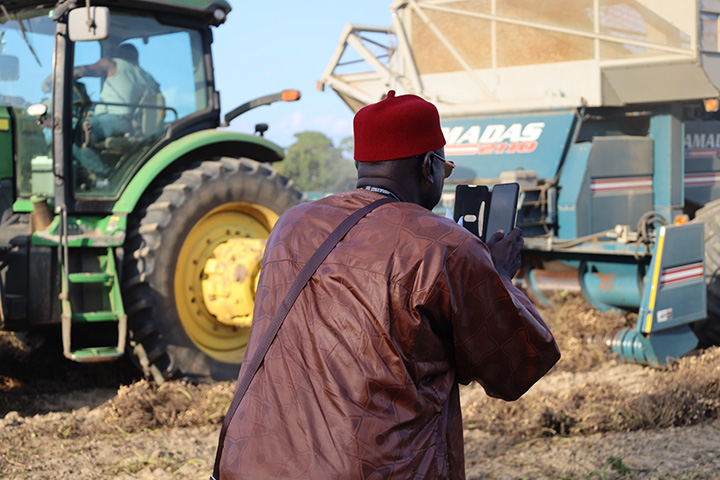 Momodou Cham of The Gambia takes video of a peanut picker running through the field as part of the Georgia Peanut Tour. (Photo by Allison Floyd)